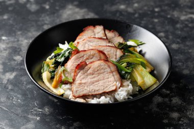 Chinese BBQ Pork Char Siu with rice and bok choy in a black bowl. clipart