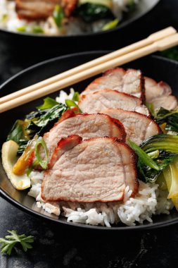 Chinese BBQ Pork Char Siu with rice and bok choy in a black bowl. clipart