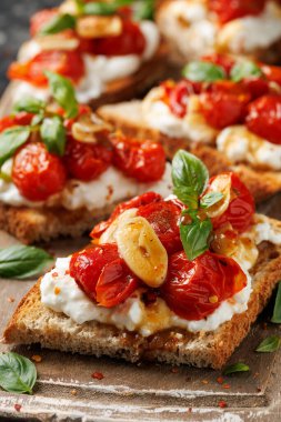 Süzme peynir ve kavrulmuş domates ahşap bir tahtanın üzerinde ekmek ekmeği tostu.