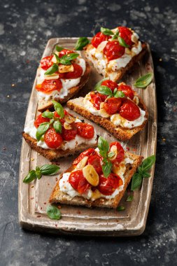 Süzme peynir ve kavrulmuş domates ahşap bir tahtanın üzerinde ekmek ekmeği tostu.