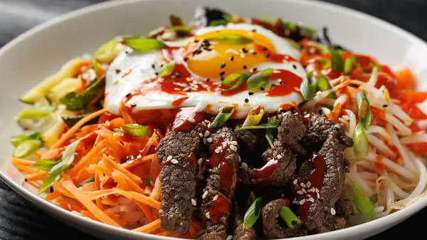 Geleneksel Kore yemeği Bibimbap, pilav, sebze sığır eti ve beyaz tabakta yumurta..