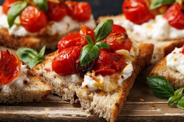 Süzme peynir ve kavrulmuş domates ahşap bir tahtanın üzerinde ekmek ekmeği tostu.