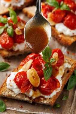 Süzme peynir ve kavrulmuş domates ahşap bir tahtanın üzerinde ekmek ekmeği tostu.