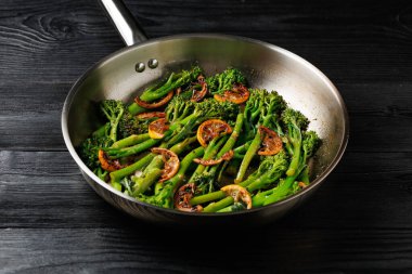 Tenderstem broccoli and charred lemon served in stainless steel frying pan. clipart