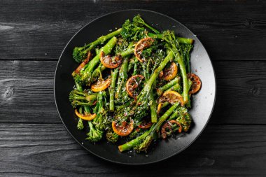 Siyah tabakta servis edilen brokoli ve kömürleşmiş limon..