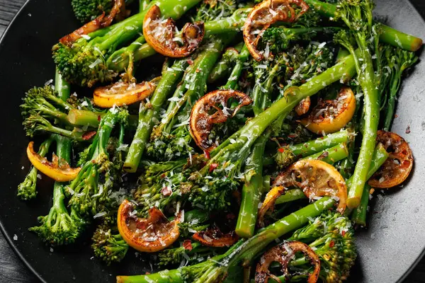 Siyah tabakta servis edilen brokoli ve kömürleşmiş limon..