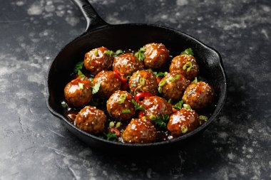 Teriyaki soslu biftek köftesi, susam çekirdeği, biber ve dökme demir bir tavada otlar..