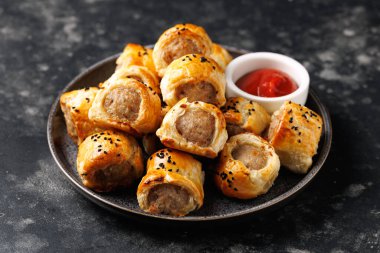 Freshly baked English Sausage rolls with ketchup. Party snack food clipart