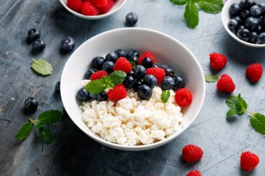 Bir kase süzme peynir, yaban mersinli peynir ve ahududu. Yüksek proteinli sağlıklı kahvaltı veya öğle yemeği.