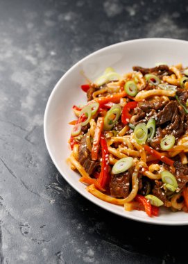 Erişteyi sığır eti ve sebzeyle karıştır. Asya usulü yemek..