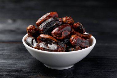Dried sweet pitted dates in white bowl. Healthy food.