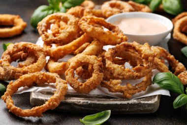 Ahşap tahtada soslu kızarmış soğan halkaları..