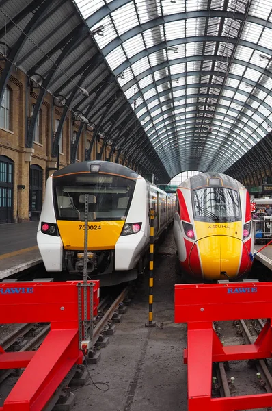 London Kings Cross station with two contrasting electric trains resting in the terminus