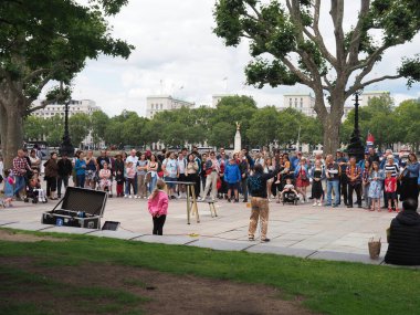 Londra 'da onları eğlendiren bir sokak sanatçısını izleyen kalabalığın yüzleri.