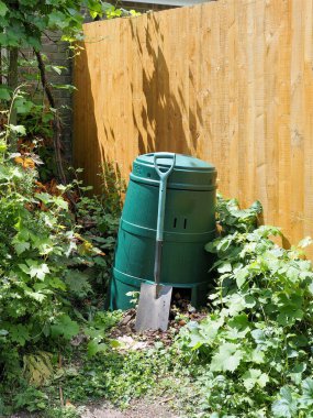 Boyalı bir çitin yanındaki gübre kutusunda dinlenen bir bahçe küreğinin dikey mahsulü