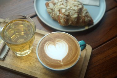 Tahta masada bir fincan sıcak latte sanat kahvesi.