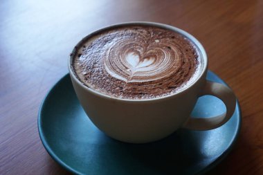 Tahta masada bir fincan sıcak latte sanat kahvesi.