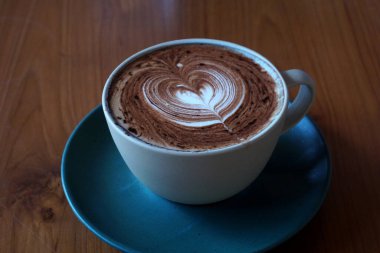 Tahta masada bir fincan sıcak latte sanat kahvesi.