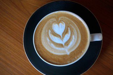 Tahta masada bir fincan sıcak latte sanat kahvesi.