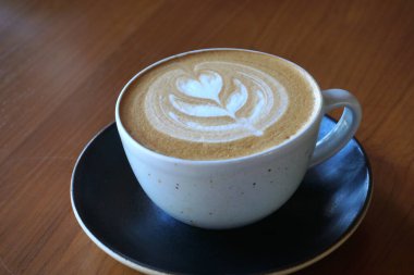 Tahta masada bir fincan sıcak latte sanat kahvesi.