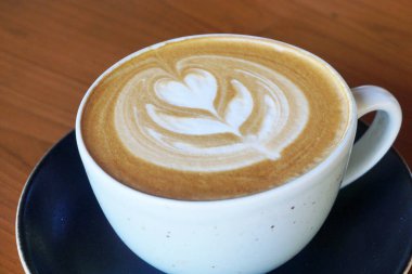 Tahta masada bir fincan sıcak latte sanat kahvesi.