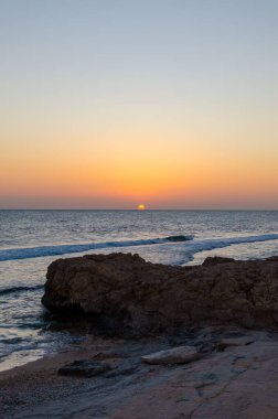 Huzurlu deniz kıyısı, gün batımı ve Mısır sahillerinde kayalar..