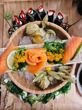 Suşi ruloları, nigiri, maki, turşu zencefil, wasabi, soya sosu ahşap tabakta ve yeşil ağaç arka planında. Japon deniz ürünleri. Yemek konsepti. Üst görünüm.