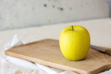 Gri arkaplandaki bambu kesme tahtasında bir elma. Taze elma dilimlenmeye hazır. Sağlıklı yaşam tarzı kavramı. Uzayı kopyala Yemek fotoğrafçılığı. 