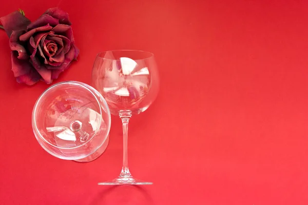 Two Empty wine glasses lies on a red background. Flat lay, top view, copy space ,minimal valentines day romance concept. Horizontal photo 