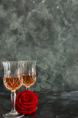 Close up two glasses of liquor and a rose on a black background. Copy space. Holiday party concept.