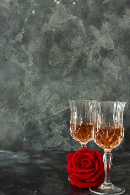 Close up two glasses of liquor and a rose on a black background. Copy space. Holiday party concept.
