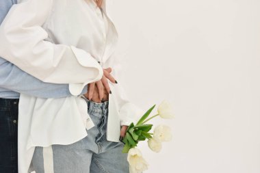 Loving couple holding a bouquet of tulips on a white background. The concept of expressing feelings of love. Copy space