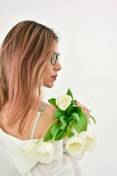 Back view of red haired woman holding bouquet of white tulips. copy space