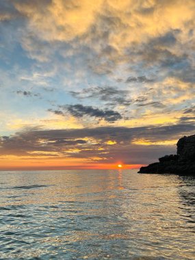Vlore Arnavutluk 'taki İoninan Denizi üzerinde günbatımı manzarası. Sakin dalgalarla dalgalanan güzel bir su. Dikey fotoğraf. Boşluğu kopyala.