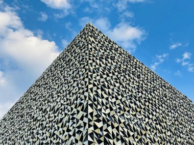 Yerden alçak açılı atış. Mavi gökyüzüne karşı bina manzarası. Minimum modern geometrik mimari şekli. Cam cephe. Modern bölge kavramı.