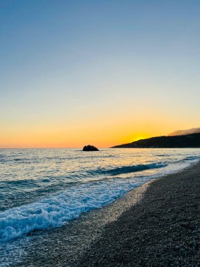 Vlore Arnavutluk 'taki İoninan Denizi üzerinde günbatımı manzarası. Sakin dalgalarla dalgalanan güzel bir su. Yatay fotoğraf. Boşluğu kopyala.