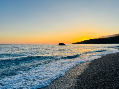 Vlore Arnavutluk 'taki İoninan Denizi üzerinde günbatımı manzarası. Sakin dalgalarla dalgalanan güzel bir su. Yatay fotoğraf. Boşluğu kopyala.