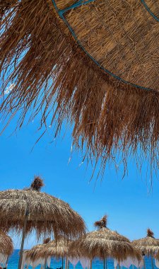 Arnavutluk 'taki İyon plajında açık mavi gökyüzü olan saman plajı şemsiyesi, Vlore. Boşluğu kopyala