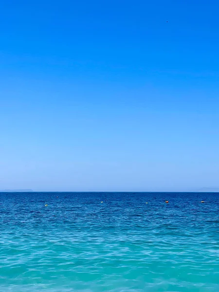 アルバニアのイオニア海のロッキービーチとクリスタルターコイズブルーの水 夏休みのコンセプト コピースペース 垂直写真 — ストック写真