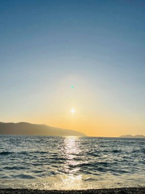 Vlore Arnavutluk 'taki İoninan Denizi üzerinde günbatımı manzarası. Sakin dalgalarla dalgalanan güzel bir su. Dikey fotoğraf. Boşluğu kopyala.
