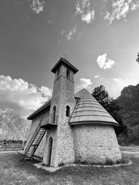 Arnavutluk 'un Theth Ulusal Parkı' ndaki Theth köyündeki Hıristiyan Kilisesi Sahnesi. Arnavut Alpleri. dikey, siyah beyaz fotoğraf. 