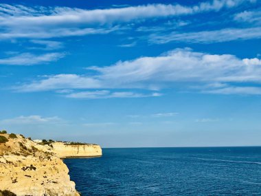Fırtınalı bir denizden yükselen mağaraları olan yüksek kireçtaşı kayalıkları. Algar Seco, Carvoeiro Güney Portekiz, Algarve. Sahildeki kumtaşından resif oluşumu. Yatay fotoğraf. Boşluğu kopyala.