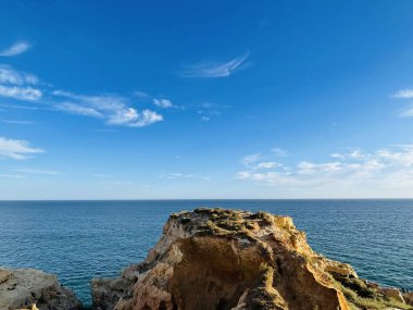 Fırtınalı bir denizden yükselen mağaraları olan yüksek kireçtaşı kayalıkları. Algar Seco, Carvoeiro Güney Portekiz, Algarve. Sahildeki kumtaşından resif oluşumu. Yatay fotoğraf. Boşluğu kopyala.