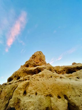 Fırtınalı bir denizden yükselen mağaraları olan yüksek kireçtaşı kayalıkları. Algar Seco, Carvoeiro Güney Portekiz, Algarve. Sahildeki kumtaşından resif oluşumu. Dikey fotoğraf. Boşluğu kopyala.