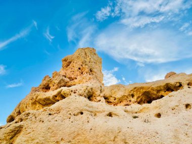 Fırtınalı bir denizden yükselen mağaraları olan yüksek kireçtaşı kayalıkları. Algar Seco, Carvoeiro Güney Portekiz, Algarve. Sahildeki kumtaşından resif oluşumu. Yatay fotoğraf. 