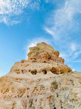 Fırtınalı bir denizden yükselen mağaraları olan yüksek kireçtaşı kayalıkları. Algar Seco, Carvoeiro Güney Portekiz, Algarve. Sahildeki kumtaşından resif oluşumu. Dikey fotoğraf. Boşluğu kopyala.