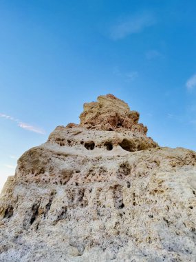 Fırtınalı bir denizden yükselen mağaraları olan yüksek kireçtaşı kayalıkları. Algar Seco, Carvoeiro Güney Portekiz, Algarve. Sahildeki kumtaşından resif oluşumu. Dikey fotoğraf. Boşluğu kopyala.