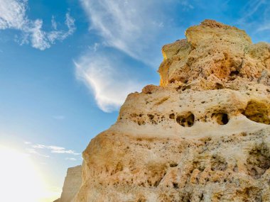 Fırtınalı bir denizden yükselen mağaraları olan yüksek kireçtaşı kayalıkları. Algar Seco, Carvoeiro Güney Portekiz, Algarve. Sahildeki kumtaşından resif oluşumu. Yatay fotoğraf. 