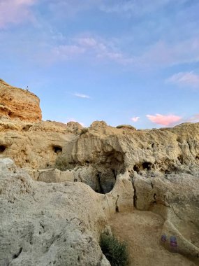 Fırtınalı bir denizden yükselen mağaraları olan yüksek kireçtaşı kayalıkları. Algar Seco, Carvoeiro Güney Portekiz, Algarve. Sahildeki kumtaşından resif oluşumu. Dikey fotoğraf. Boşluğu kopyala.