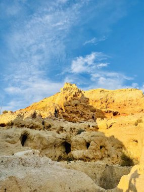 Fırtınalı bir denizden yükselen mağaraları olan yüksek kireçtaşı kayalıkları. Algar Seco, Carvoeiro Güney Portekiz, Algarve. Sahildeki kumtaşından resif oluşumu. Dikey fotoğraf. Boşluğu kopyala. 